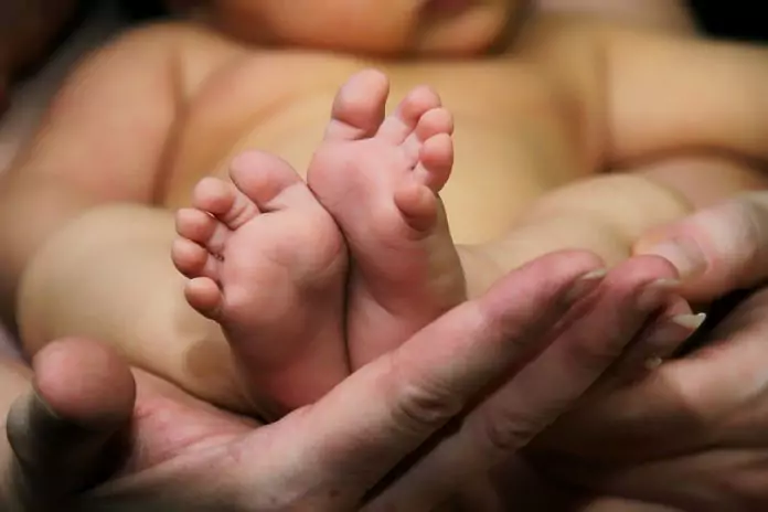 barefoot baby in his mother's hands