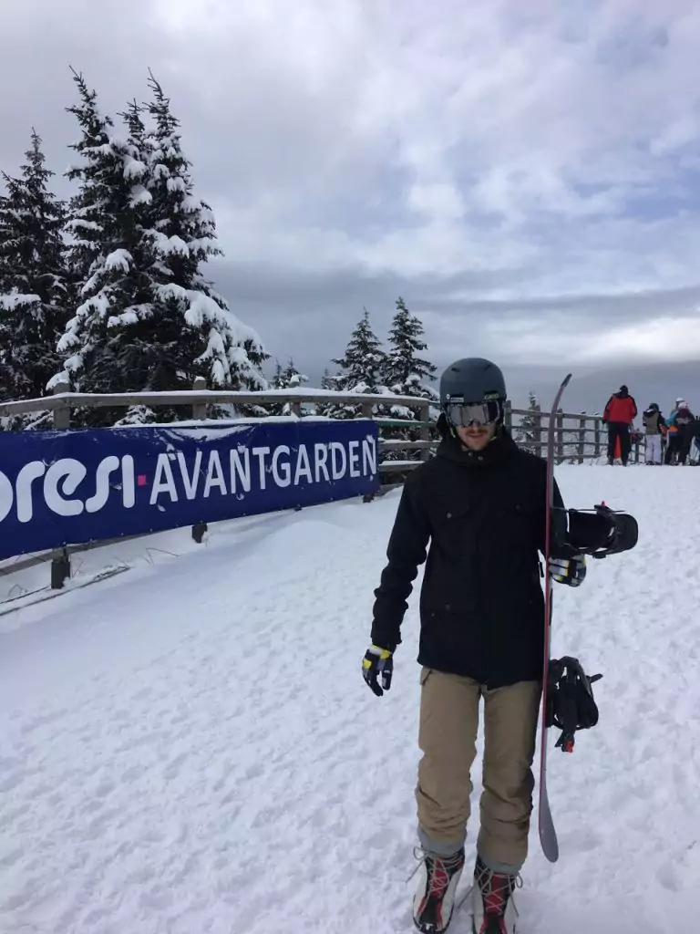 a men walking in the snow with a snowboard in his hand