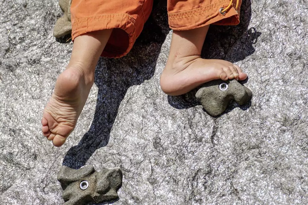 a barefoot child climbing rocks