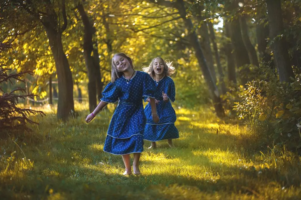 young girls run barefoot in the forest with blue dress 