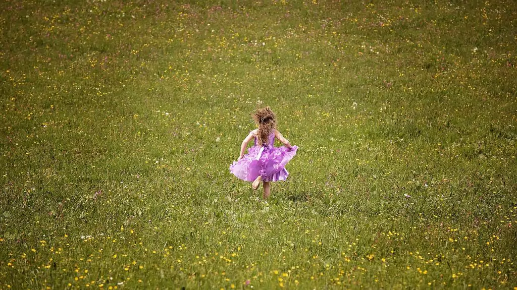 a child running barefoot in the fields in a purple dress
