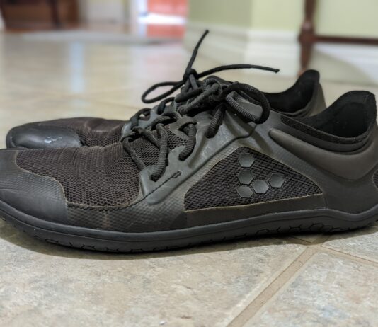 Side view of worn, black minimalist shoes